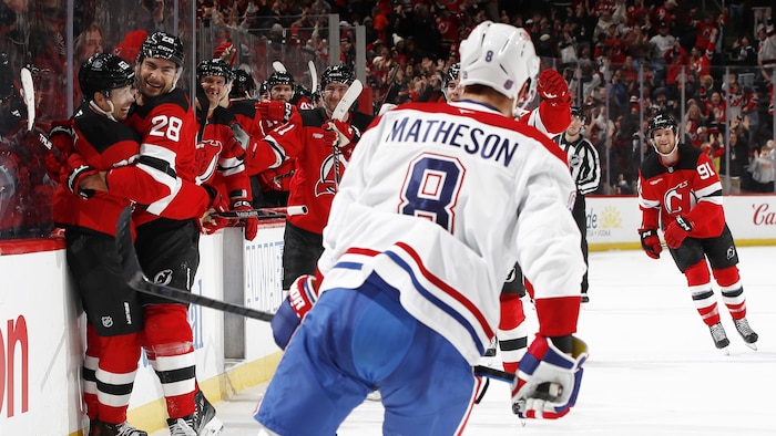 Des joueurs de hockey célèbrent leur victoire devant un adversaire.