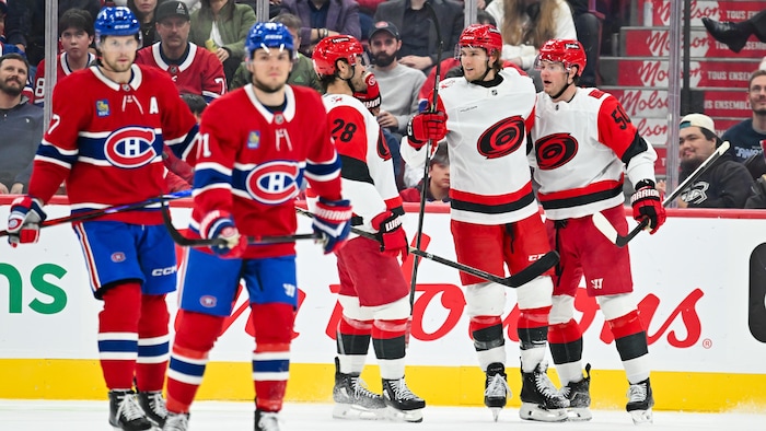 Trois joueurs de hockey célèbrent un but à côté de deux adversaires.