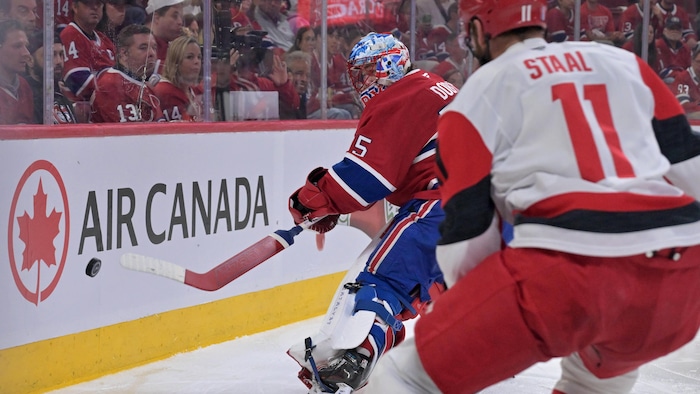 Le gardien du Canadien Jakub Dobes prend contrôle du disque derrière son filet, surveillé par Jordan Staal des Hurricanes.