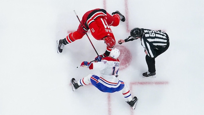 Deux joueurs de hockey attendent que l'arbitre mette la rondelle en jeu.