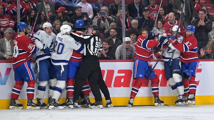 Des joueurs de hockey se chamaillent et un arbitre tente de les séparer.