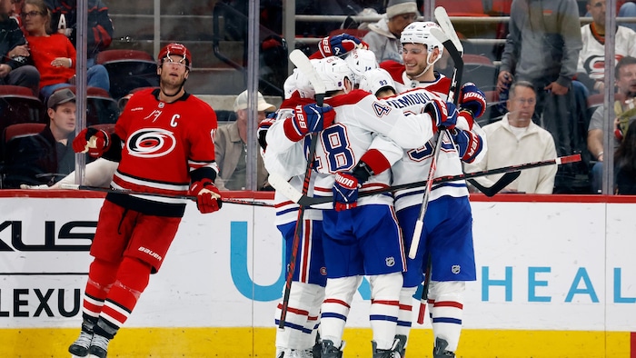 Des hockeyeurs célèbrent un but près d'un rival.