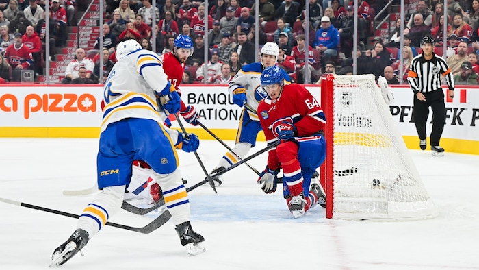 Un joueur de hockey marque un but malgré la présence d'un adversaire devant le filet.