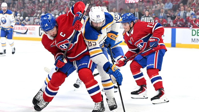 Des joueurs de hockey se disputent la rondelle. 