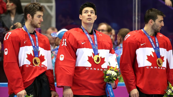 Trois joueurs de hockey avec leurs médailles d'or.