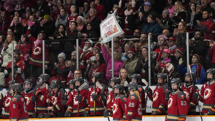 Des partisans de hockey et des joueuses applaudissent en appui à une entraîneuse malade.