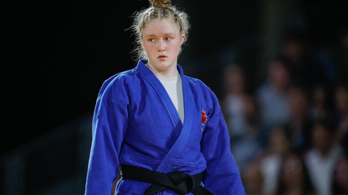 Une judoka debout regarde à sa droite.