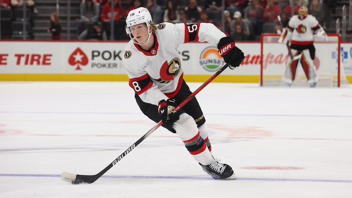 Un jeune joueur de hockey patine en possession de la rondelle pendant un match professionnel.
