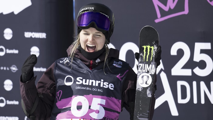 Cassie Sharpe célèbre son podium avec ses skis en main.