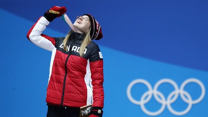 Elle tient sa médaille dans la main droite et regarde vers le ciel.