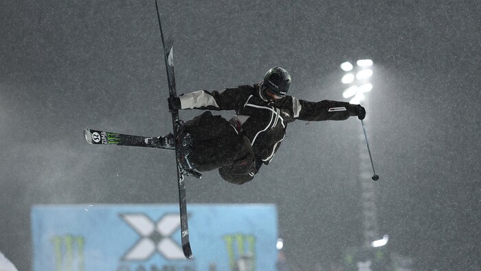 Une skieuse acrobatique effectue une figure pendant une épreuve de demi-lune.