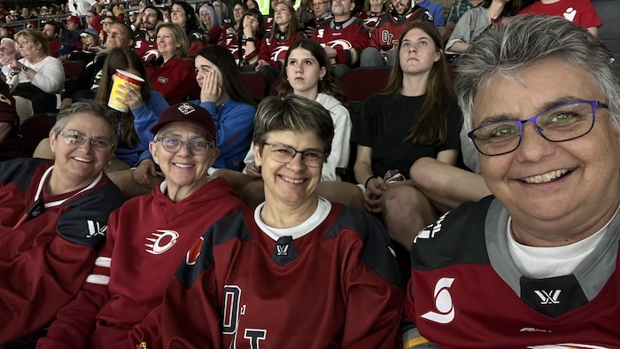 Des partisanes de hockey prennent une photo lors d'un match.