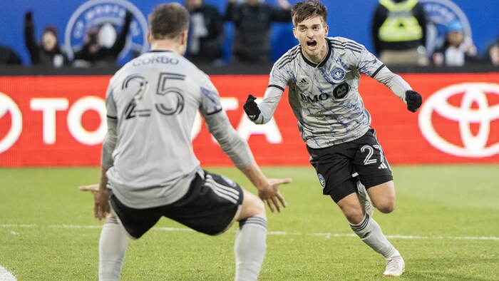 Un joueur de soccer semble crier en se dirigeant vers un coéquipier.