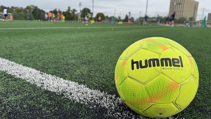 Un ballon de soccer est placé bien évidence sur le côté d'un terrain pendant un entraînement de soccer féminin.
