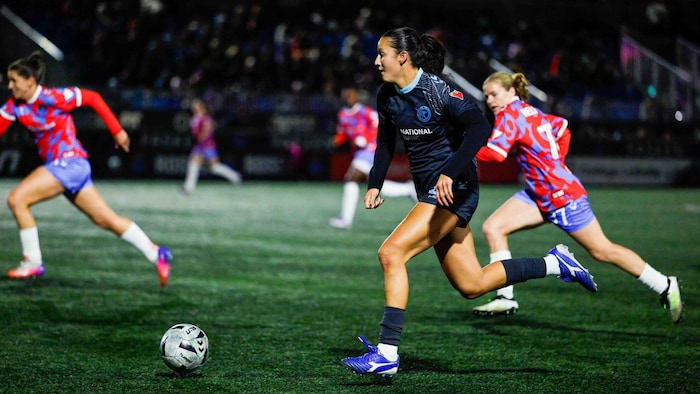 Une joueuse de soccer avance avec le ballon pendant un match professionnel.