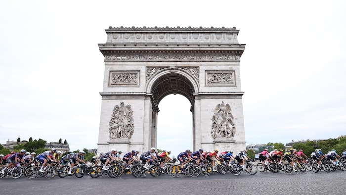 Des cyclistes roulent devant l'Arc de Triomphe à Paris.