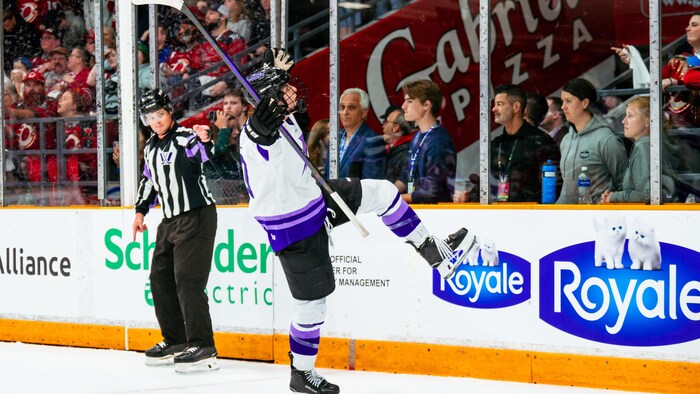 Une joueuse de hockey lève les bras au ciel pour célébrer un but.