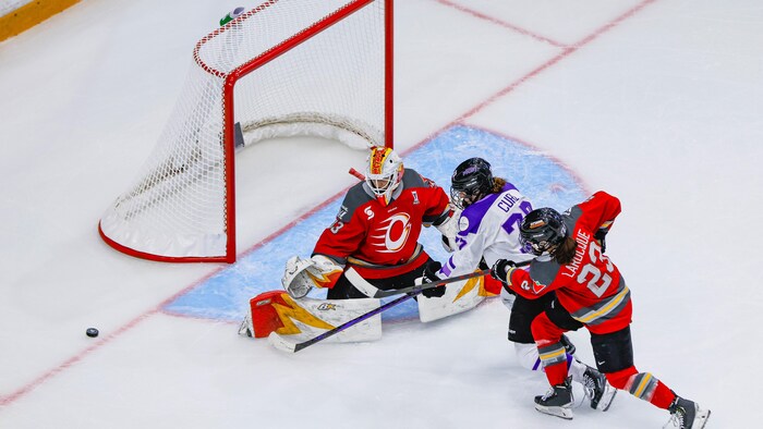 Une joueuse de hockey frappe à la porte du but adverse pendant une rencontre.