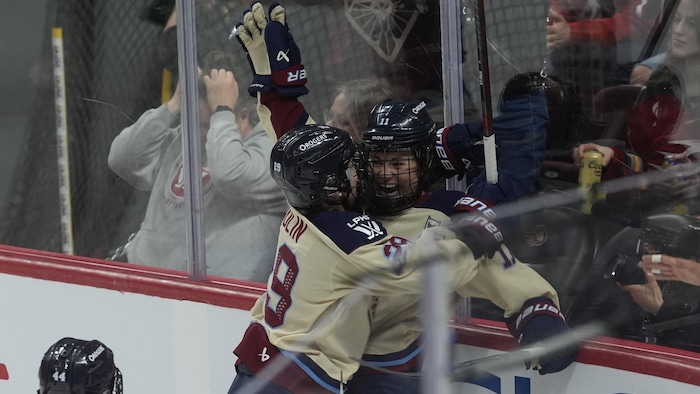 Deux joueuses de hockey professionnelle se donnent un câlin après un but.