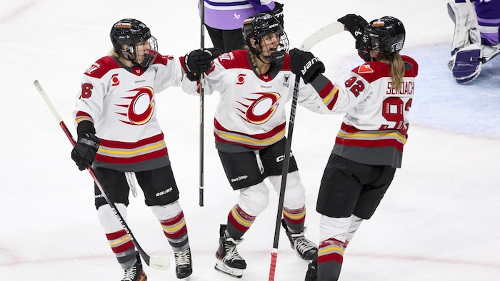 Des joueuses de hockey célèbrent un but. 