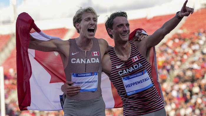 Charles Philibert-Thiboutot et Robert Heppenstall célèbrent le doublé canadien au 1500 mètres avec un drapeau canadien autour des épaules sur la piste d'athlétisme des Jeux panaméricains à Santiago au Chili