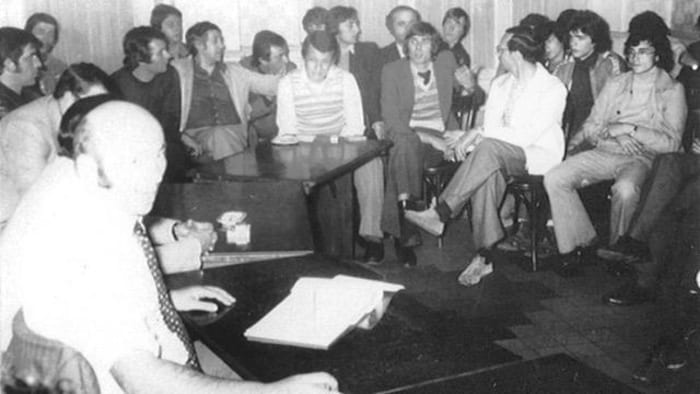 Une photo en noir et blanc d'une vingtaine d'hommes assis autour d'une table.