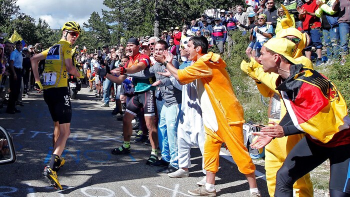 Chris Froome, vêtu d'un maillot jaune, court tout en étant encouragé par des spectateurs lors du Tour de France de 2016.