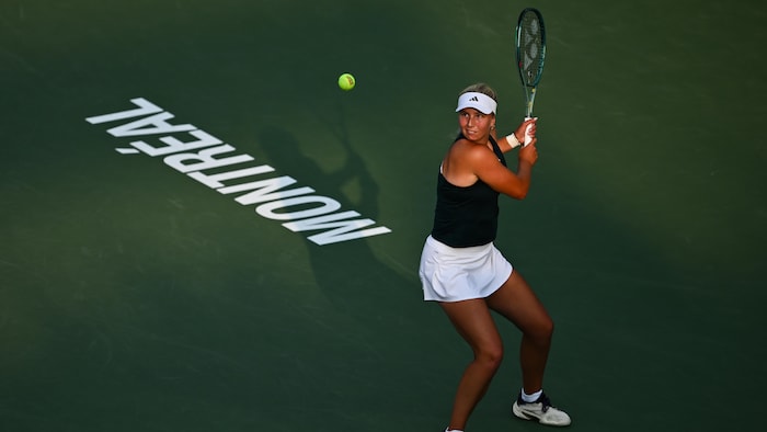 Une joueuse de tennis regarde la balle et se prépare à faire un revers. 