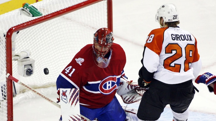 Un joueur de hockey inscrit un but contre un gardien.