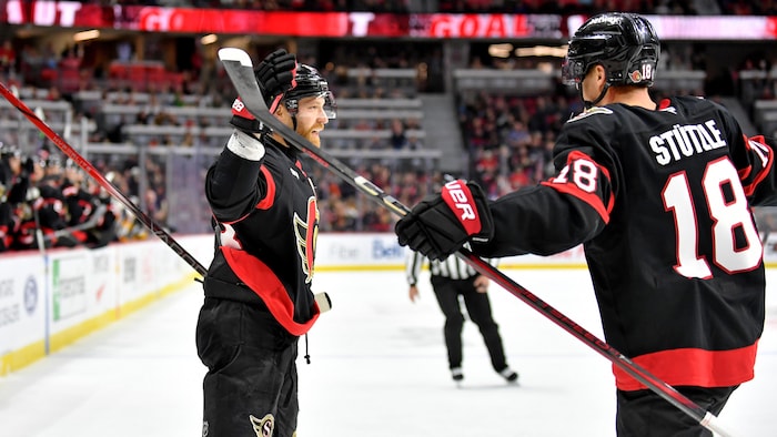 Un joueur de hockey professionnel lève le bras dans les airs après avoir marqué un but.