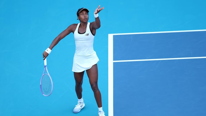 Une joueuse de tennis lance la balle pour servir.