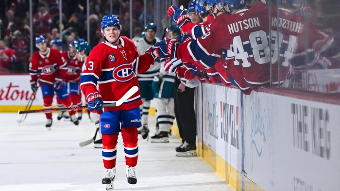 Un joueur de hockey est félicité au banc de son équipe.