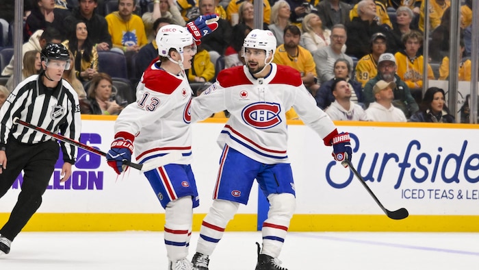 Deux joueurs célèbrent un but devant l'arbitre et la foule. 