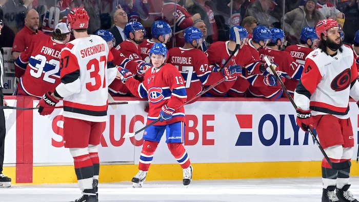 Un joueur de hockey tape dans la main de ses coéquipiers au banc des joueurs.