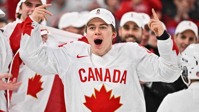 Connor Bedard célèbre la victoire du Canada avec les bras dans les airs.