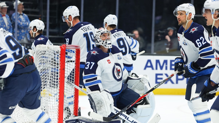 Des joueurs de hockey patinent autour de leur gardien. 