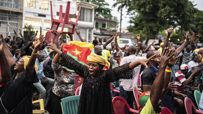 Des partisans de soccer lèvent les bras au ciel pour célébrer un but lors d'un rassemblement dans les rues.