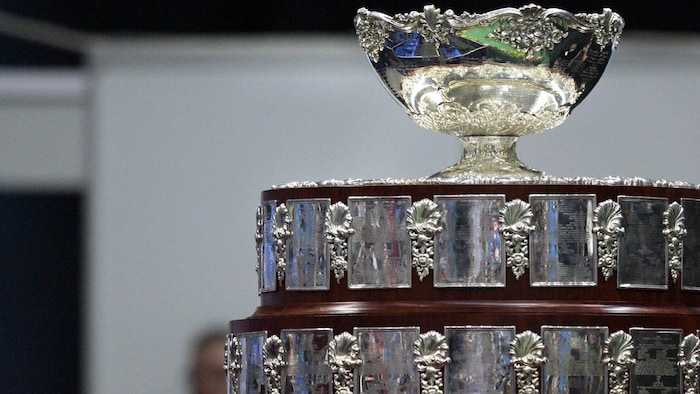 Gros plan d'un trophée avec une coupe au sommet sur un socle orné de plaques argentées.