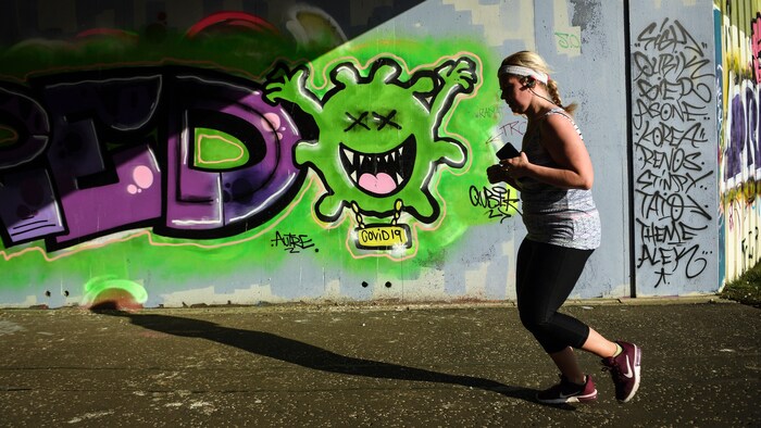 Elle passe devant un mur couvert de graffitis.