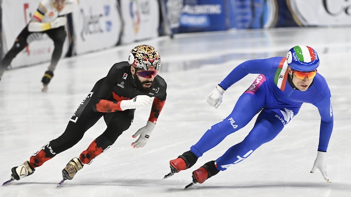Deux patineurs de vitesse sont côte à côte durant la course du relais mixte. 
