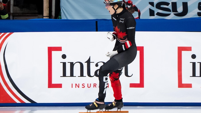 La patineuse Courtney Sarault serre le poing en guise de célébration en se laissant glisser sur la glace. 