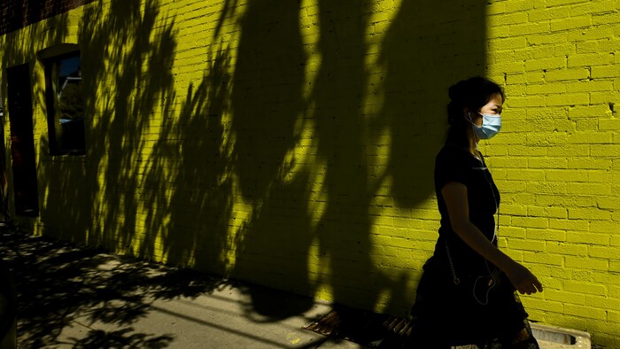 Une femme portant un masque marche dans la rue.