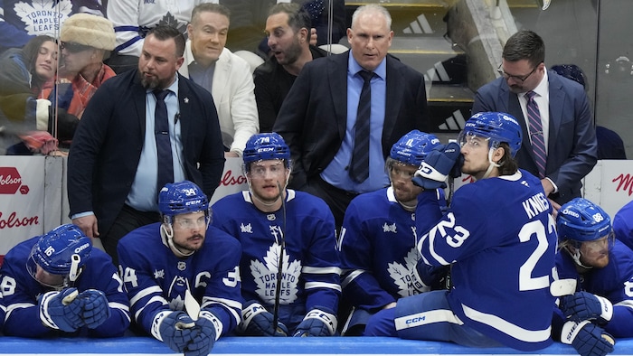 Des joueurs et des entraîneurs à leur banc, la mine basse
