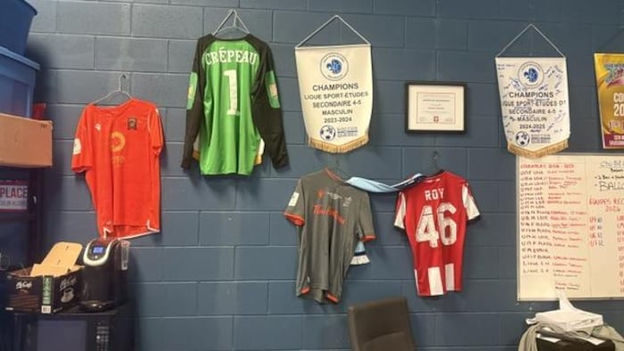 Des maillots de soccer sont accrochés au mur d'un bureau.