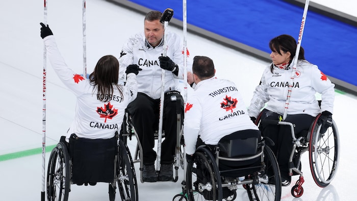 Les quatre joueurs de l'équipe canadienne de curling en fauteuil roulant se rassemblent pour s'encourager au début de leur finale contre la Chine.