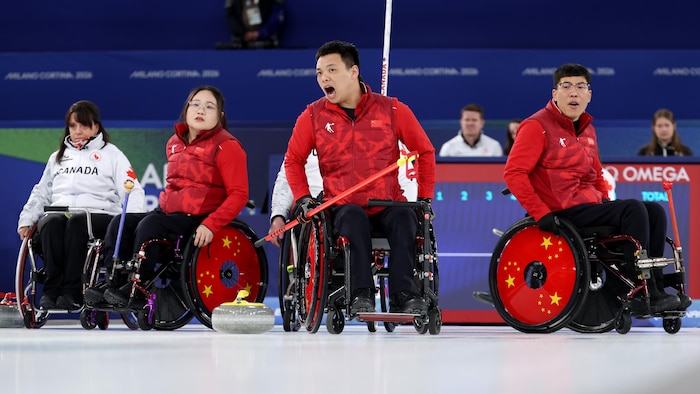 Zhang Mingliang et deux de ses coéquipiers de l'équipe chinoise de curling en fauteuil roulant regardent une pierre s'éloigner.