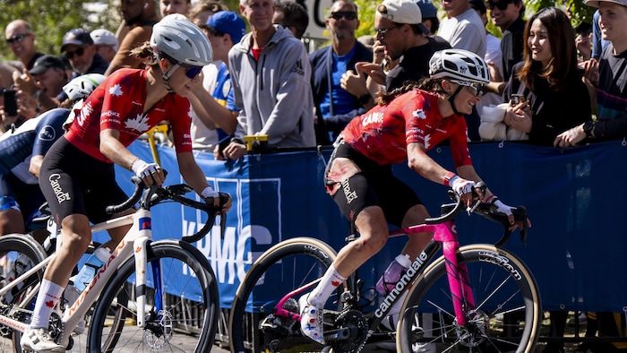 Deux cyclistes abordent un virage. L'une d'elles a le cuissard déchiré en raison d'une chute.