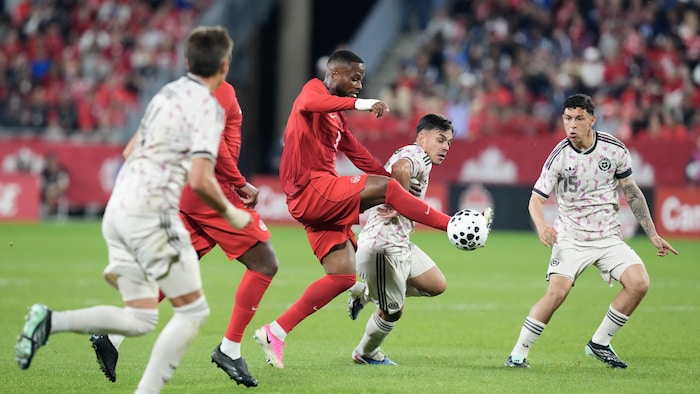 Un joueur de soccer contrôle un ballon dans les airs.