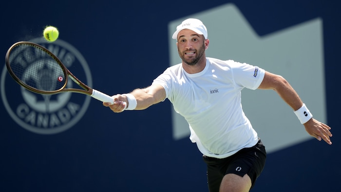 Le joueur de tennis retourne une balle.