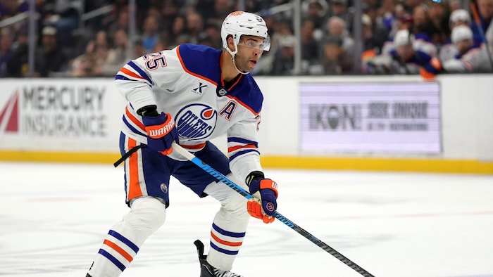 Il patine avec la rondelle, dans un uniforme des Oilers.